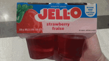 a person is holding a box of strawberry jello in their hand