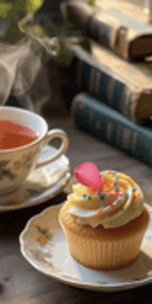 a cup of tea and a cupcake on a saucer on a table .