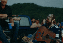 a man in a dallas cowboys shirt plays a guitar
