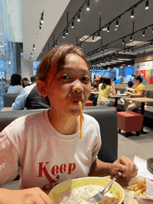 a girl wearing a keep t-shirt is eating a meal