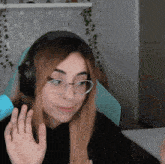 a woman wearing headphones and glasses is waving