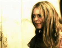 a woman with long blonde hair is smiling and looking to the side