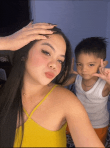 a woman in a yellow top is taking a picture with a young boy