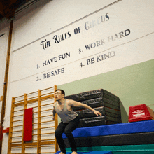 a man is doing a trick in front of a wall that says the rules of circus