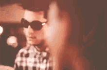 a man wearing sunglasses is standing next to a woman .