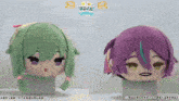 two stuffed dolls with green hair and purple hair are on display