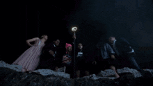 a group of people are standing next to each other in a dark room holding glowing wands .