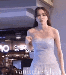 a woman in a white dress is walking down a runway in front of a crowd .