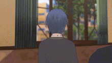 a man with blue hair is sitting in front of a window in a room looking out .