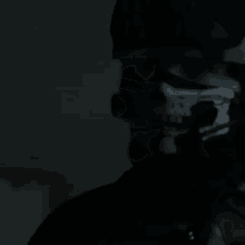 a man with a skull mask on his face is holding a gun in the dark .