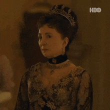 a woman wearing a tiara and a black choker is standing in a room .