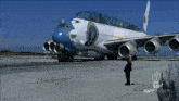 a man stands next to a large airplane that says oatestudios on the bottom