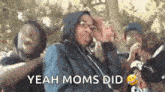 a group of people standing next to each other with the words `` yeah moms did '' written on the screen .