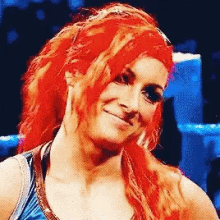 a woman with red hair is wearing a blue tank top and smiling