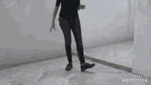 a woman in a black shirt is walking in front of a white wall with the words made in animatica below her