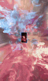 a picture of a man in a red scarf is surrounded by pink and blue smoke