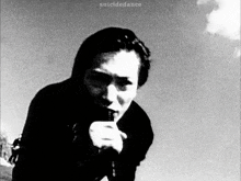 a black and white photo of a man smoking a cigarette .