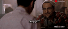 a man wearing glasses and a plaid shirt is talking to another man and the words cangguh are on the screen
