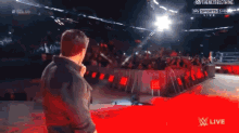 a man stands on a red carpet in front of a crowd at a live wrestling show