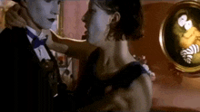 a man and a woman are dancing in a room with a painting on the wall behind them .