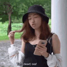 a woman wearing a black hat is holding a cell phone .