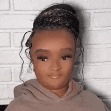a young girl with braids in a bun is wearing a hoodie .