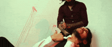 a man with a tattoo on his arm is holding a knife over a man laying on the floor