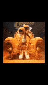 a cheetah is sitting on a chair with a cheetos logo behind him