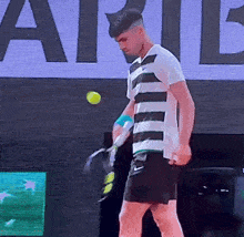 a man in a striped shirt holds a tennis racquet