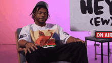 a man sits in a chair in front of a sign that says hey crew