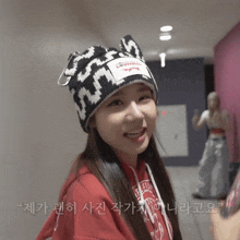 a woman wearing a red sweatshirt and a black and white hat with the word everlast on the front