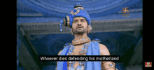 a man in a blue turban is standing in front of a building .