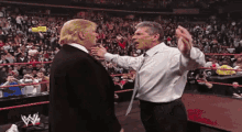 two men are standing next to each other in a wrestling ring and one of them has a w on his shirt