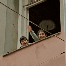 a boy and a girl are looking out a window