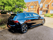 a black car is parked in front of a brick house with a license plate that says ' tf34 lv '