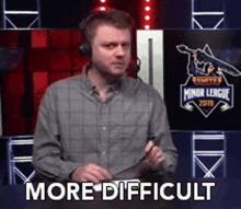 a man wearing headphones is standing in front of a sign that says more difficult .