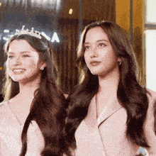 two women are standing next to each other and one has a tiara on