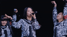 a girl singing into a microphone while wearing a shirt that says ag