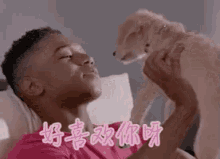 a man is laying on a bed with a puppy on his lap .