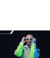 a man wearing sunglasses and a neon jacket looks at the camera