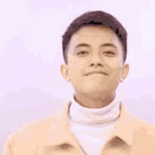 a young man wearing a yellow jacket and a white turtleneck is smiling with a yellow circle in the background .