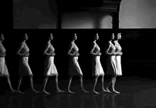 a black and white photo of a woman walking in a row .