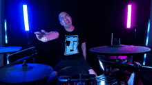 a man wearing a shirt with the letter r on it is playing drums