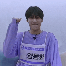 a young man wearing a purple shirt and an apron with yang donghwa on it