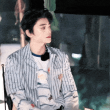 a young man wearing a striped shirt is sitting in a chair with his eyes closed