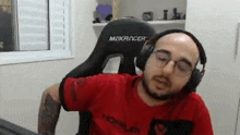 a man wearing headphones and a red shirt is sitting in a chair .