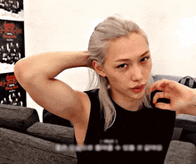 a man with long blonde hair is sitting on a couch with his hands behind his head .