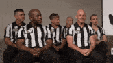 a group of men wearing aew striped shirts sit in a row