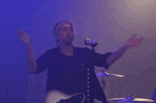 a man is singing into a microphone while holding a guitar