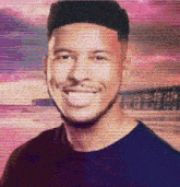 a man in a black shirt is smiling in front of a pink sky